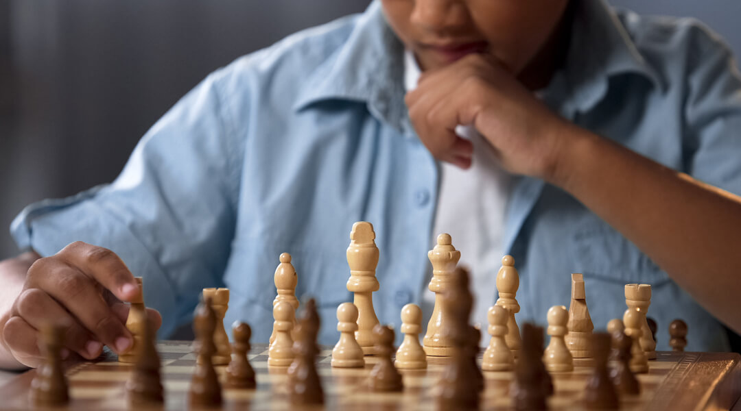 Chess board with teenager in background, situated as the opponent