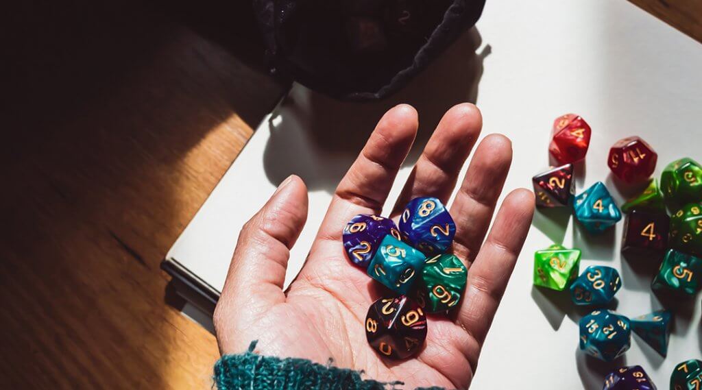 Image of a hand holding various colored and shaped role-playing dice