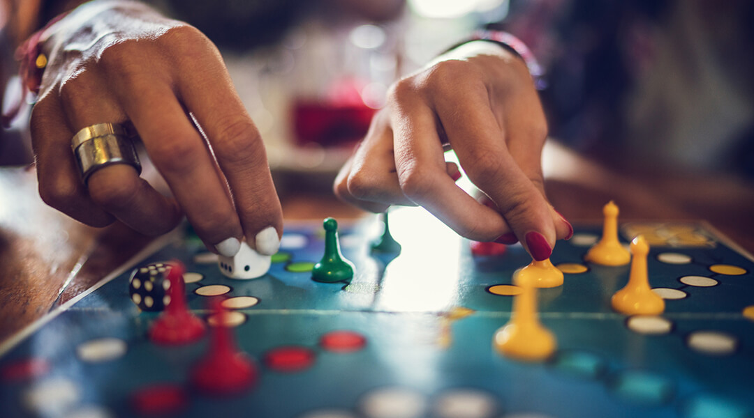 Close up of people playing a board game with game pieces and dice