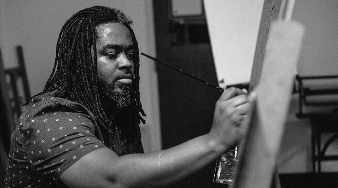 Pittsburgh artist Cue Perry painting canvas with a paintbrush