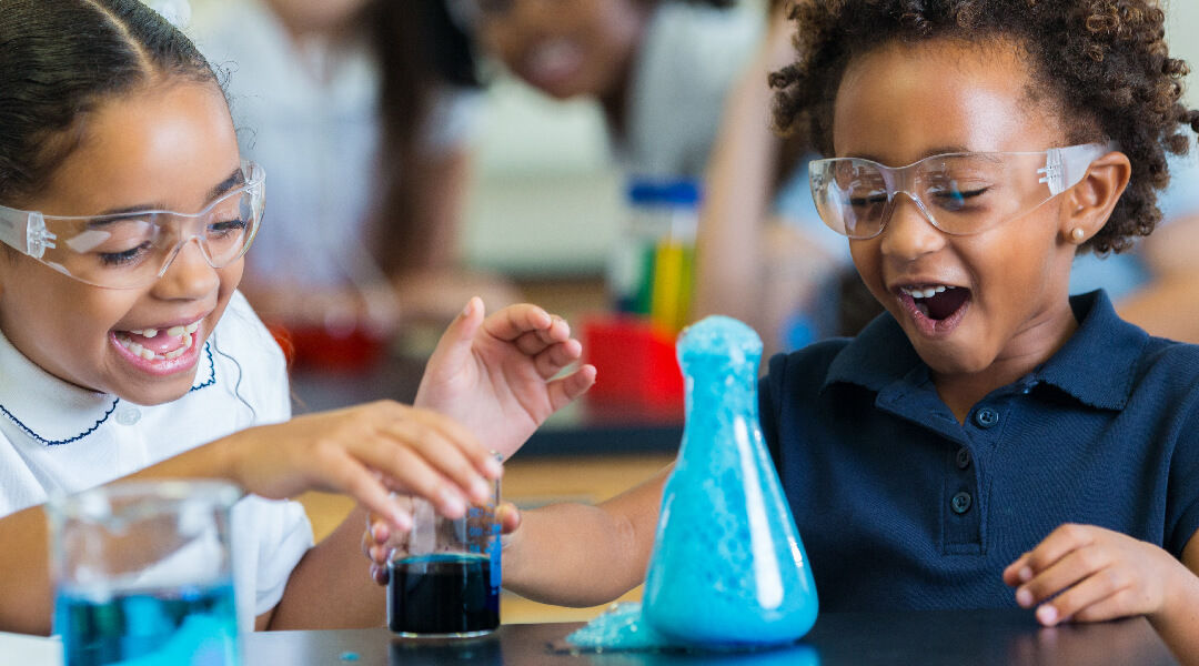 Two children wearing safety goggles doing a science experiment.