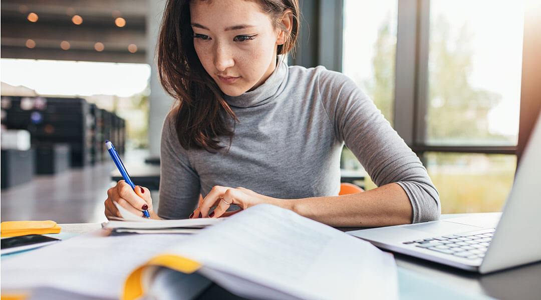 Close up image of a college student doing assignments in library.