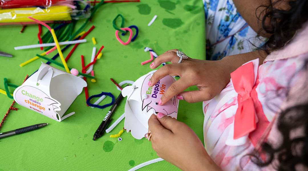 A child crafts a piggy bank out of paper and pipe cleaners