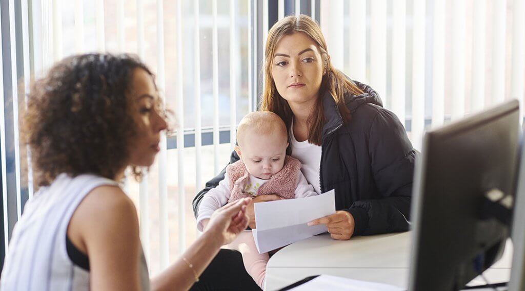 Young adult with baby on lap meeting with support worker