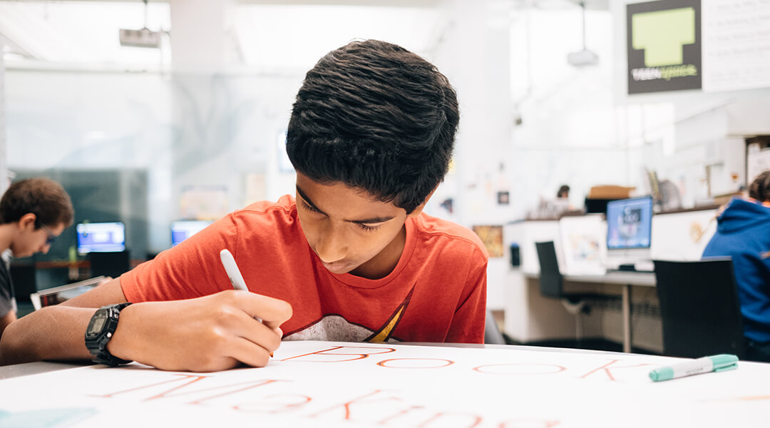 A teen draws on posterboard in the library's Teen Space.