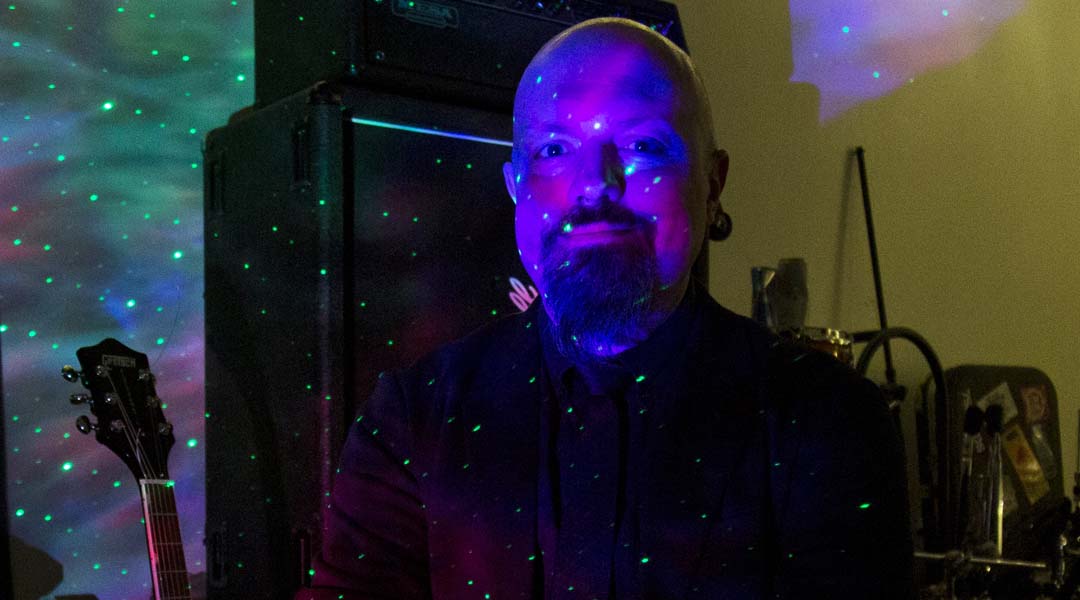 Neon lights illuminate musician Luke Ferdinand's face.