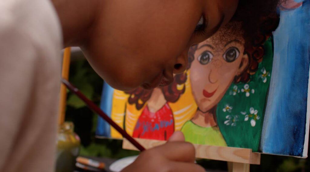 Detail of a child painting at an easel.