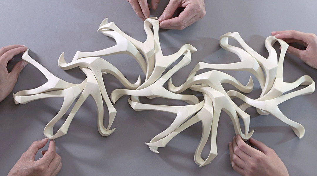 Detail of hands manipulating interlocking white 3D sculpture parts
