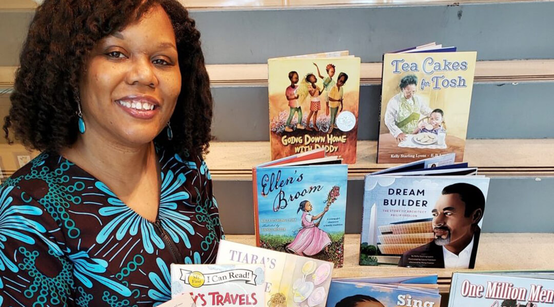 Pittsburgh author Kelly Starling Lyons posing with a collection of children's books she wrote. Photo credit: Melissa Campbell