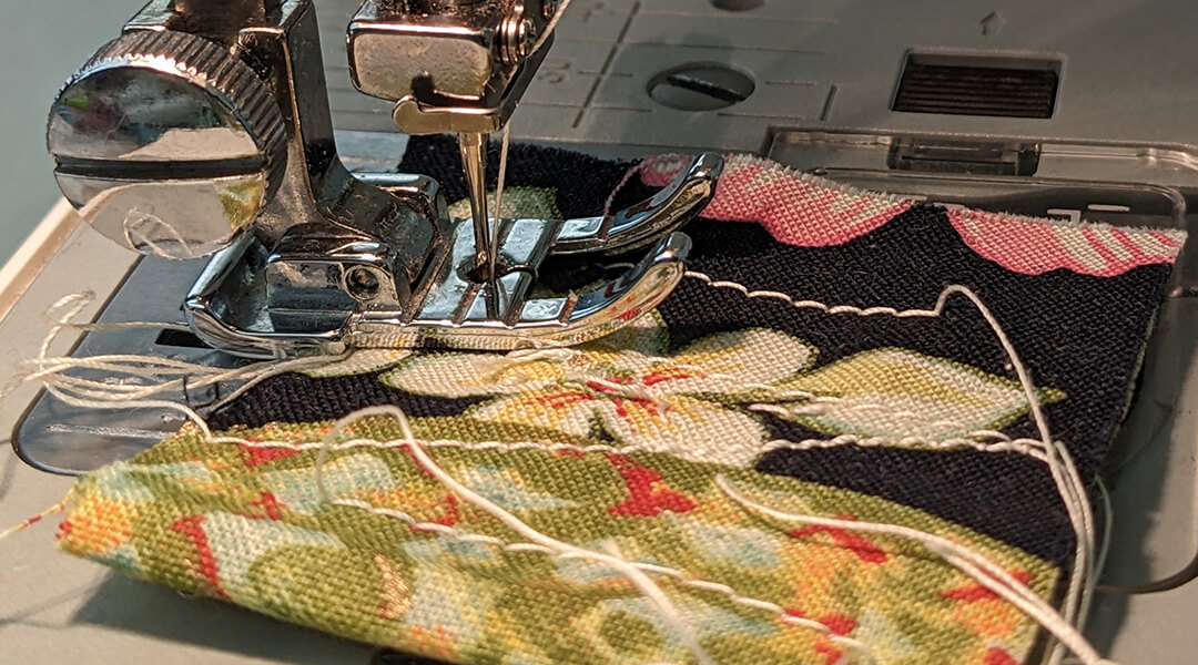 Fabric being run through a sewing machine.