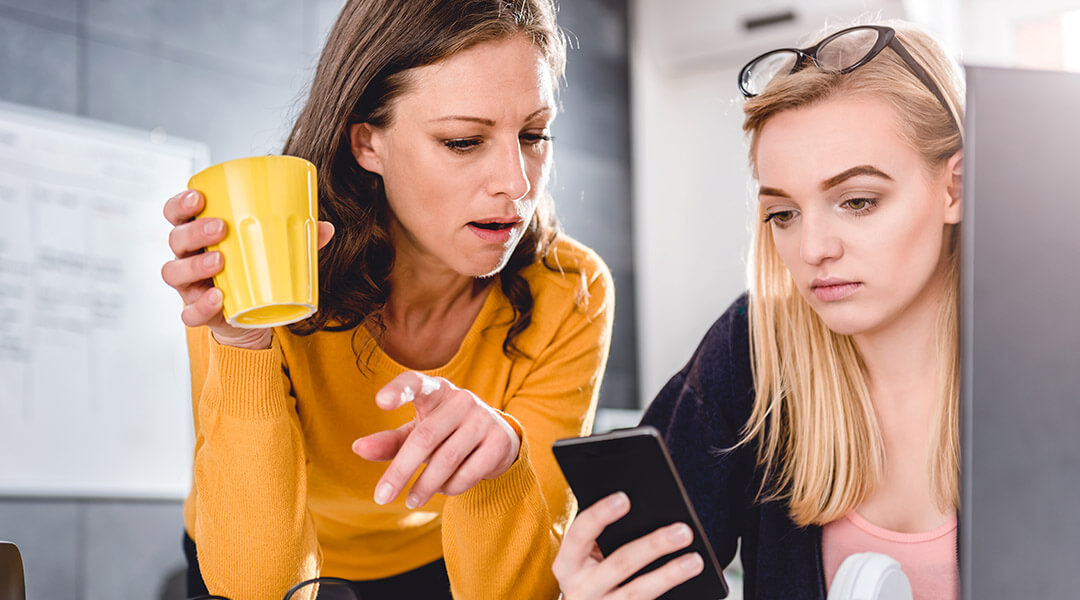 Two business woman working together at the office and using smart phone