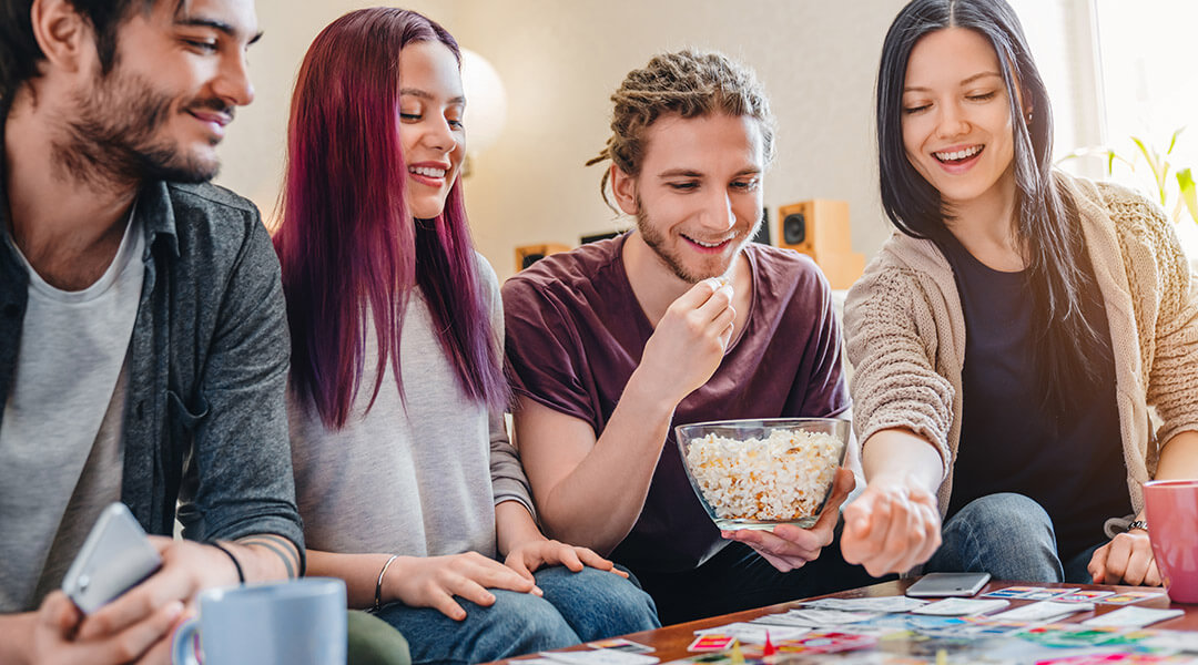 Four young adults enjoy playing a board game together.