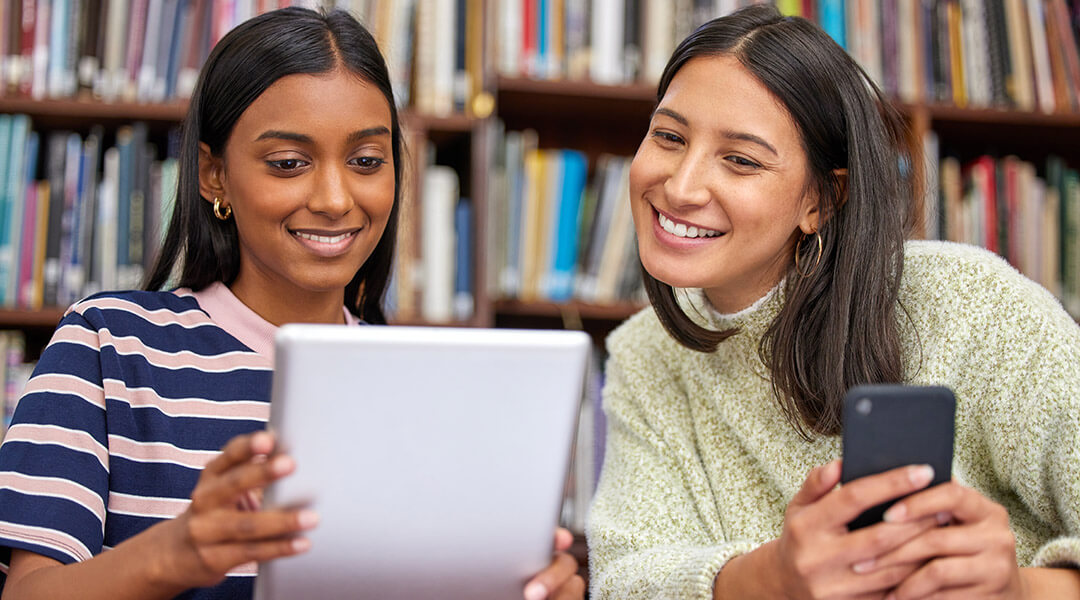 Two young adults share content from their tablet and cell phone.