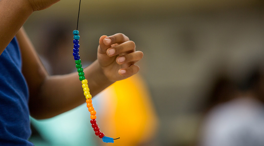 Colorful beads on a string are held up by a child.