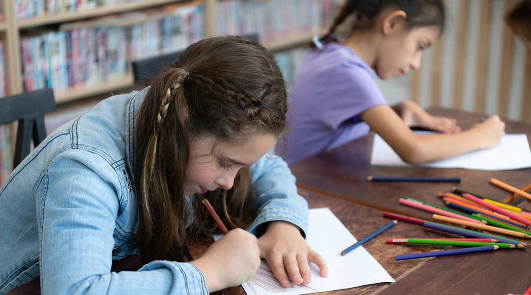 Two children draw with colored pencils.