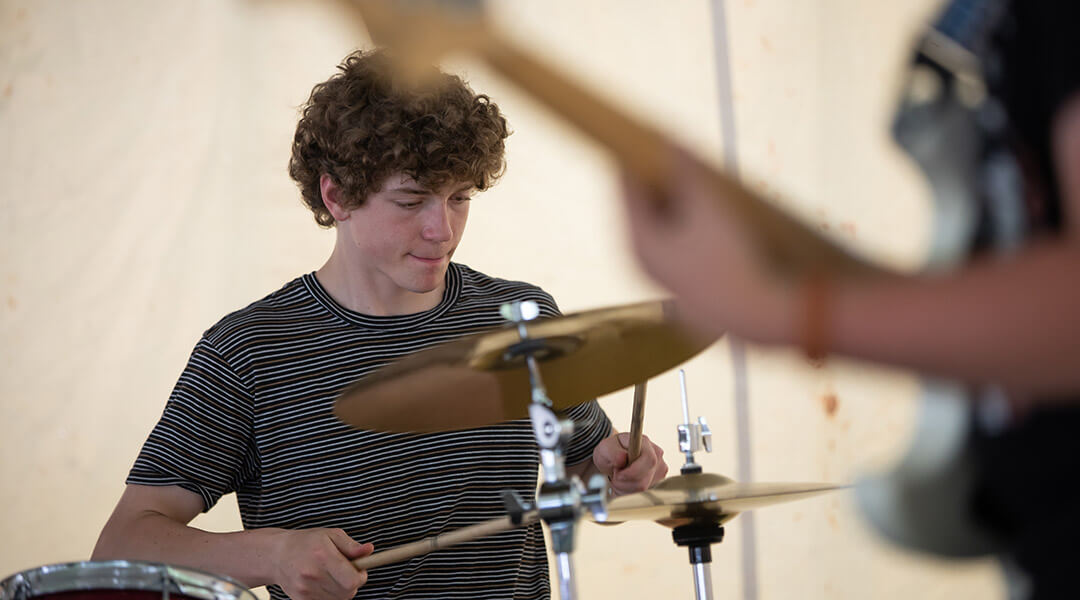 A teenager plays the drums.