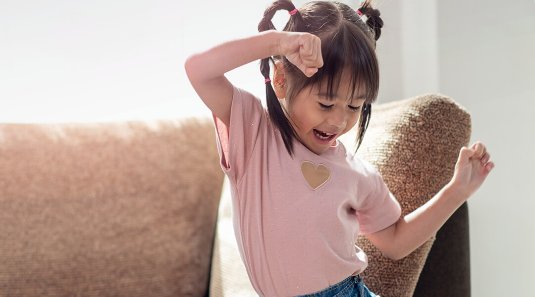 A young child dances in their living room.