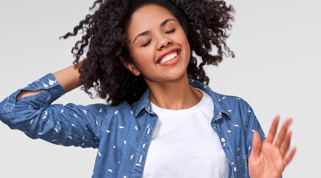 Stock photo of a teenager dancing with their eyes closed.