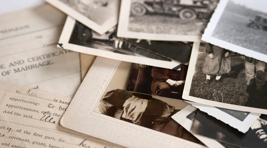 A collection of old photographs and local records spread on a table.