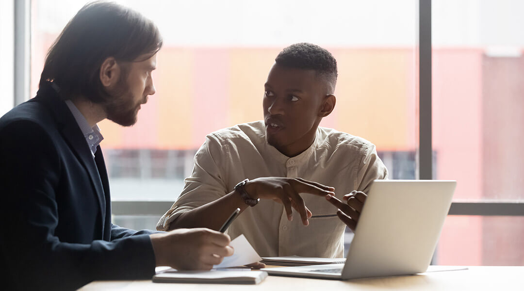 An employee reviews information in a meeting with their colleague.