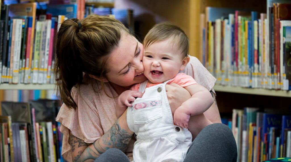 A baby laughs with their caregiver during storytime.