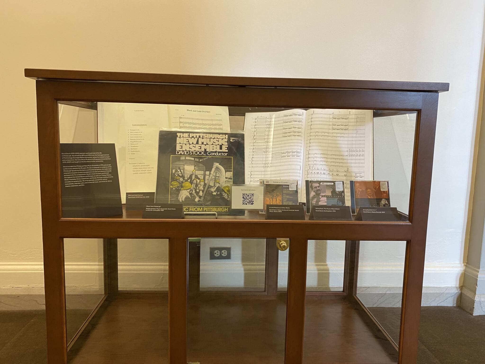 Glass and wood display cabinet featuring records, CDs and written music.