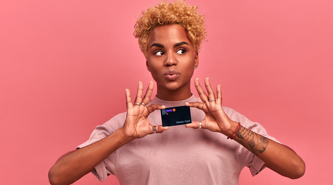 Person with blond curly hair and a pink tshirt holding a CLP library card