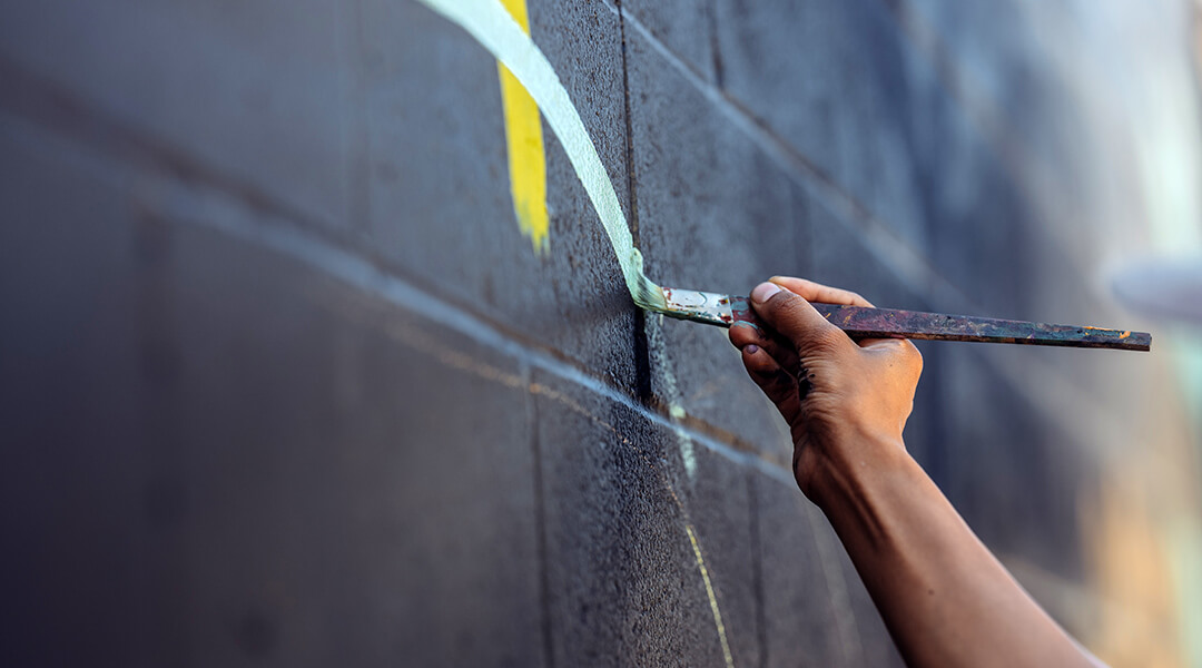 Hand close up of a mural artist creating wall art.