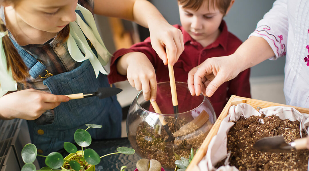 Three children put soil into a small bowl for a terrarium.
