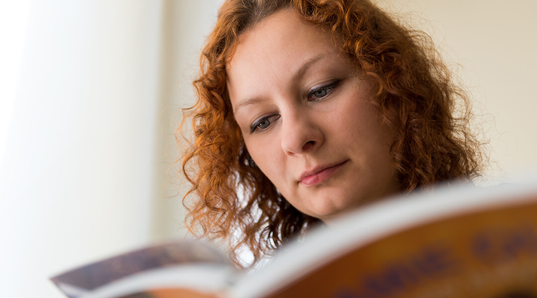 Close-up image of a young adult reading a graphic novel.