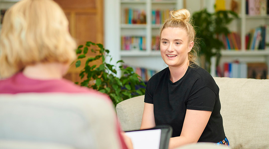 A young adult is interviewed in an office.