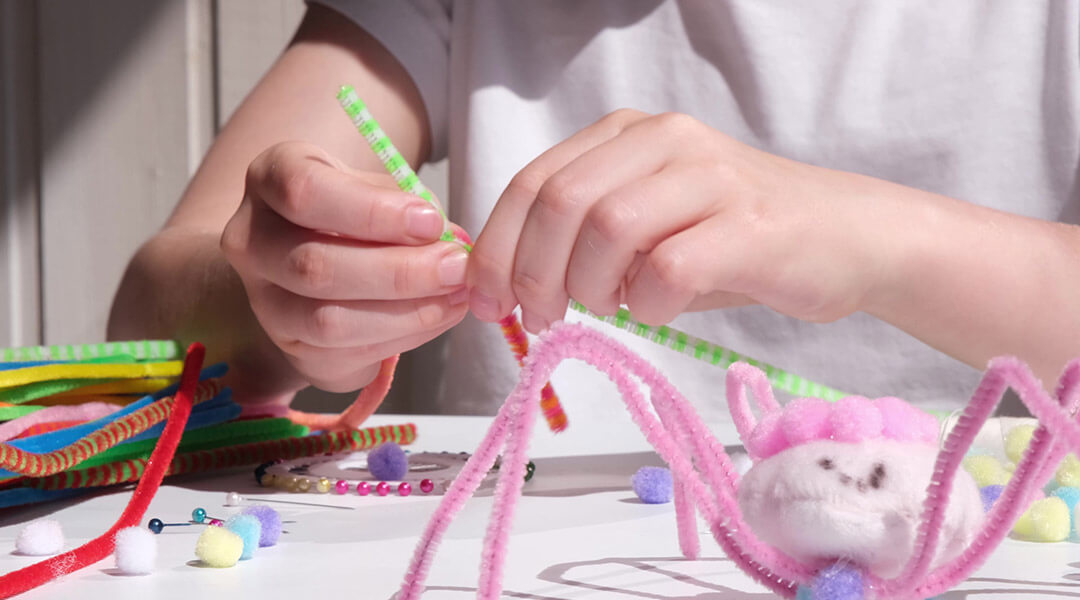 Close-up of a child's hands as they make a craft with pipe cleaners.