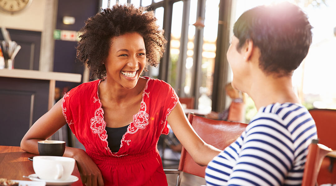 Two adult friends talking at a coffee shop