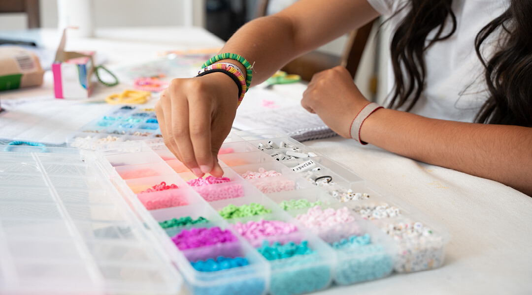 Close-up of a teen choosing beads from a set to make friendship bracelets.