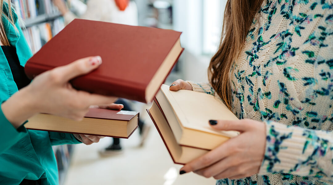 Two adults exchanging books in a library.