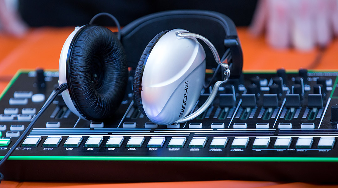 Close-up of a large pair of headphones resting on top of a synthesizer.