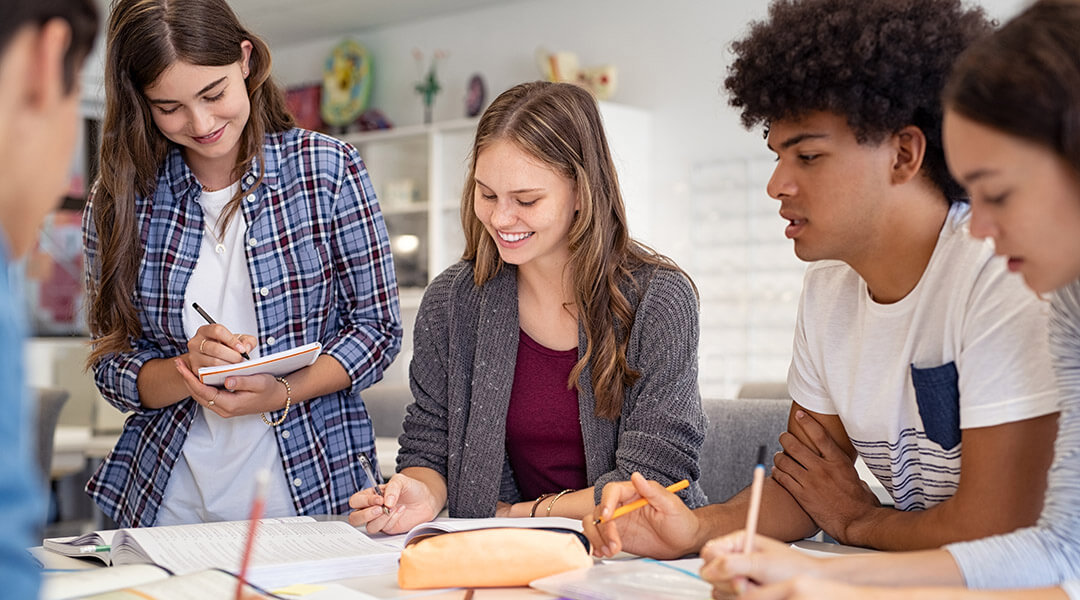 Happy group of high school students work on a group project together.